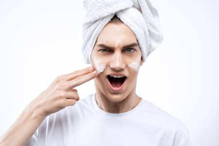 A handsome man applies an anti-wrinkle moisturizer to his face.male cosmetology.の写真素材