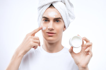 A handsome man applies an anti-wrinkle moisturizer to his face.male cosmetology.の写真素材