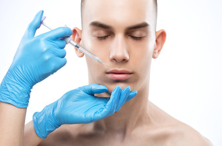 Men's cosmetology. Beautician makes a man a rejuvenation injection procedure on his face.の写真素材