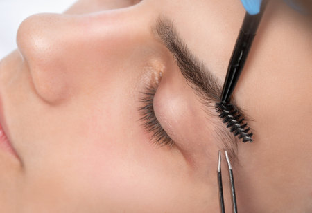 The makeup artist plucks the eyebrows of a handsome young man. Professional make-up and face care.の写真素材