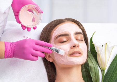 Beautician makes a face mask of a woman to rejuvenate the skin. Cosmetology treatment of problem skin on the face and body.の写真素材