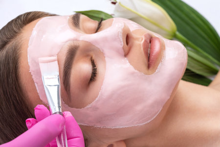 Beautician makes a face mask of a woman to rejuvenate the skin. Cosmetology treatment of problem skin on the face and body.の写真素材