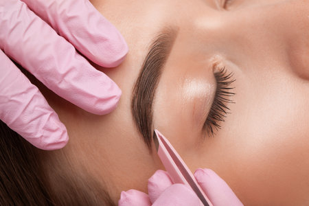 Makeup artist plucks eyebrows after dyeing in a beauty salon. Professional make-up and cosmetic skin care.の写真素材