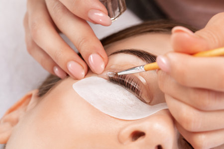 Make-up artist makes the procedure of lamination and dyeing of eyelashes to a beautiful woman in a beauty salon. Eyelash extensions. Eyelashesの写真素材