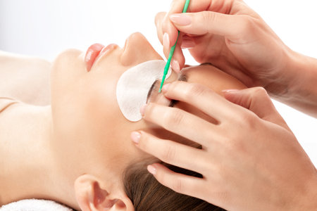 Make-up artist makes the procedure of lamination and dyeing of eyelashes to a beautiful woman in a beauty salon. Eyelash extensions. Eyelashesの写真素材