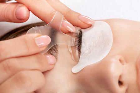 Make-up artist makes the procedure of lamination and dyeing of eyelashes to a beautiful woman in a beauty salon. Eyelash extensions. Eyelashesの写真素材
