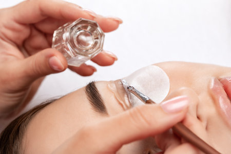 Make-up artist makes the procedure of lamination and dyeing of eyelashes to a beautiful woman in a beauty salon. Eyelash extensions. Eyelashesの写真素材