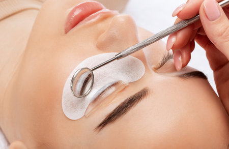 Make-up artist makes the procedure of lamination and dyeing of eyelashes to a beautiful woman in a beauty salon. Eyelash extensions. Eyelashesの写真素材