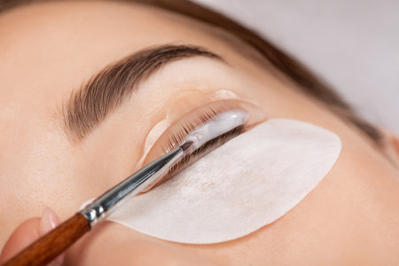 Make-up artist makes the procedure of lamination and dyeing of eyelashes to a beautiful woman in a beauty salon. Eyelash extensions. Eyelashesの写真素材