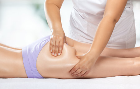 Masseur makes anti-cellulite massage on the legs, thighs, hips and buttocks in the spa. Overweight treatment, body sculpting.Cosmetology and massage concept.の写真素材