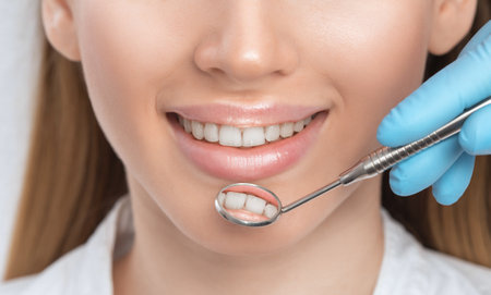 A dentist doctor treats caries on a tooth of a young beautiful woman in a dental clinic. Tooth filling.の写真素材