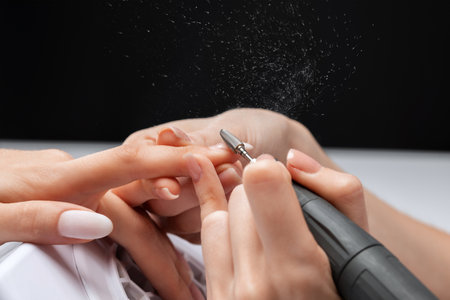 The master of the manicure saws and attaches a nail shape during the procedure of nail extensions in the beauty salon. Professional care for hands.の写真素材