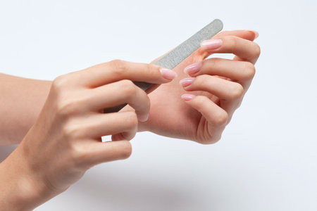the girl saws with a nail file and shaped her nails during the nail extension procedure in a beauty salon. professional hand care.の写真素材