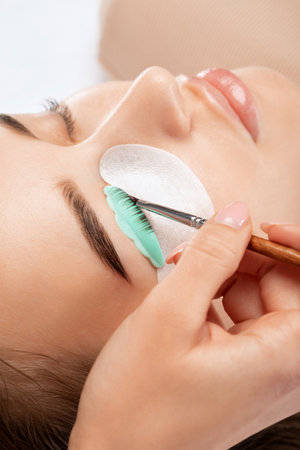 Make-up artist makes the procedure of lamination and dyeing of eyelashes to a beautiful woman in a beauty salon. Eyelash extensions. Eyelashesの写真素材
