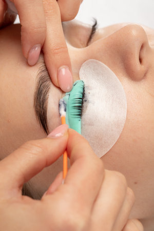 Make-up artist makes the procedure of lamination and dyeing of eyelashes to a beautiful woman in a beauty salon. Eyelash extensions. Eyelashesの写真素材
