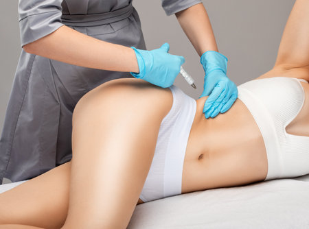 cosmetologist makes lipolytic injections to burn fat on the stomach and waist of a woman. Female aesthetic cosmetology in a beauty salon.Cosmetology concept.の写真素材