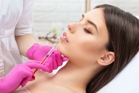 Injections for lips augmentation anti wrinkle injections on the face of a beautiful woman. Female aesthetic cosmetology in a beauty salon.の写真素材