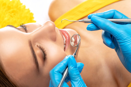 A dentist doctor treats caries on a tooth of a young beautiful woman in a dental clinic. Tooth filling.の写真素材