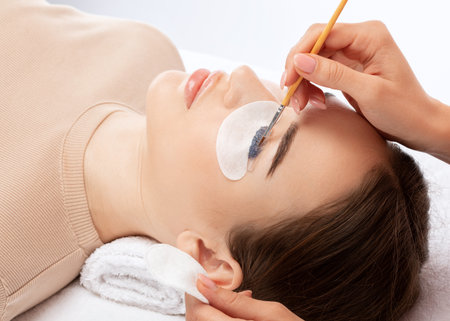 Make-up artist makes the procedure of lamination and dyeing of eyelashes to a beautiful woman in a beauty salon. Eyelash extensions. Eyelashesの写真素材