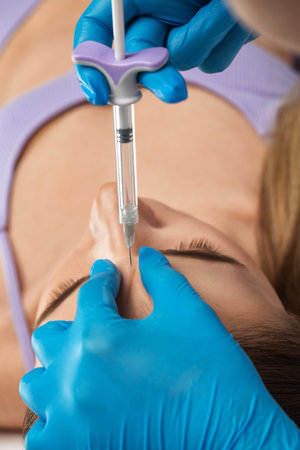 Cosmetologist does injections for lips augmentation and anti wrinkle in the nasolabial folds of a beautiful woman. Women's cosmetology in the beauty salon.の写真素材
