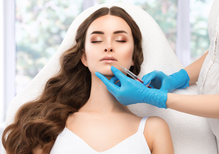 Cosmetologist does injections for lips augmentation and anti wrinkle in the nasolabial folds of a beautiful woman. Women's cosmetology in the beauty salon.の写真素材