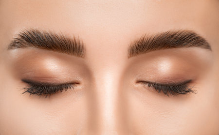 The make-up artist does Long-lasting styling of the eyebrows and will color the eyebrows. Eyebrow lamination. Professional make-up and face care.の写真素材