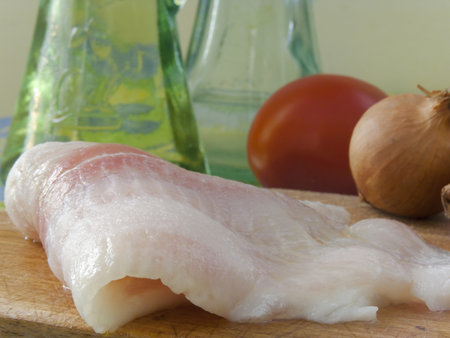 Raw fillet of a fish Pangasius hypophthalmus on a wood board