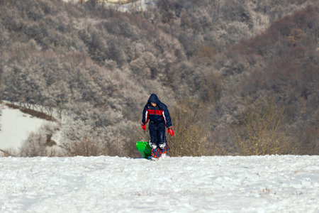 Boy pulling sled on a hill covered with snowの写真素材