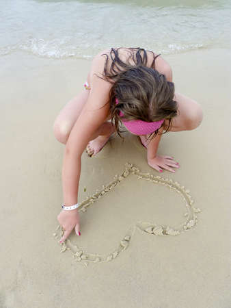 Little girl heart line in the sand on the beachの写真素材