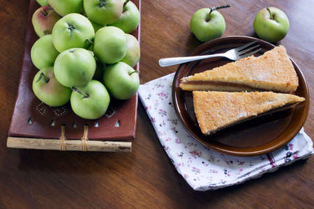 Slice of freshly baked apple pie served at the table with fresh applesの写真素材