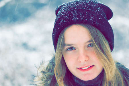 Girl aged 12, walks in the winter with cap covered with snow.Vintage stylized photoの写真素材
