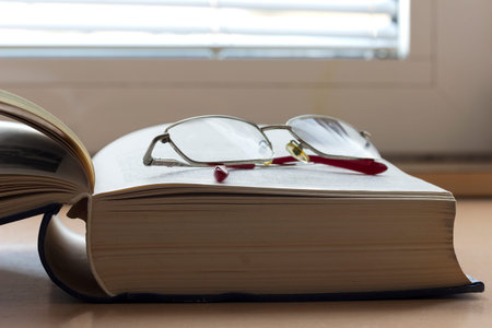 Open book on a table with reading glassesの写真素材