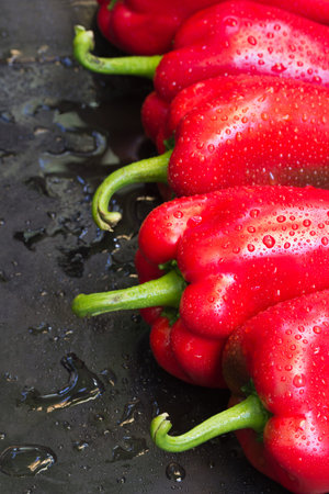 Red sweet fresh peppers on dark background
