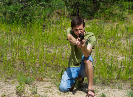 Portrait of a young man taking aim with a pneumatic gun kneeling