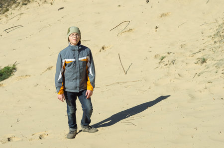 A boy stands on the sandy shore of the river Stugnaの写真素材