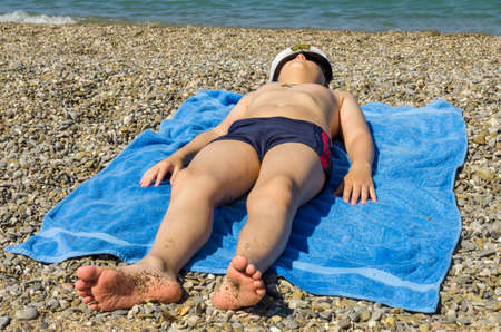Ten-year boy sunbathes on a beachの写真素材