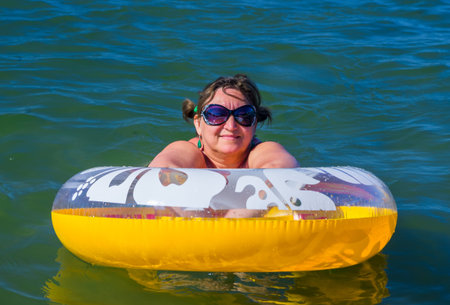 Woman in sunglasses on the inflatable buoy swimming in a seaの写真素材