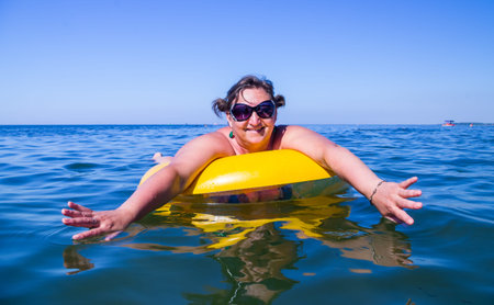 Woman in sunglasses on the inflatable buoy swimming in a seaの写真素材