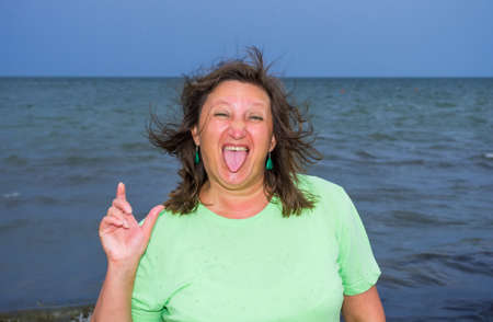 The woman on a background of the storm sea stuck out her tongueの写真素材