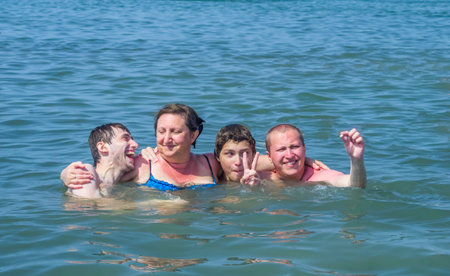 Mother and her three sons enjoy sitting at sea on summer vacationの写真素材