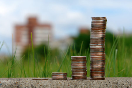 Stack of coins on a background of green grass and citiesの写真素材