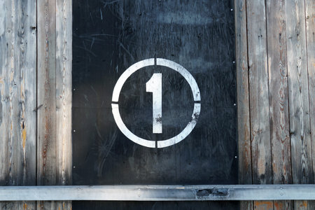 Number 1 in circle, on old rubber banner on stadium wall. White winner stamp with scratches on black...