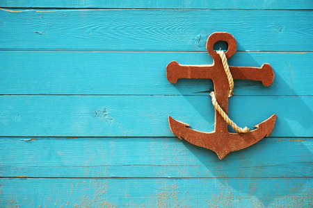 Decorative wooden sea anchor on blue wooden board. Children's nautical theme. Photo