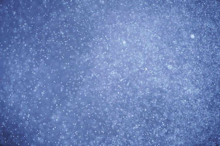 Abstract festive background with selective focus. Bright particles on dark background. Splashes, space, energy flow with defocused bokehの写真素材