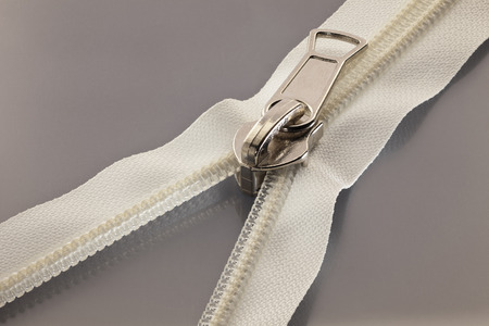 studio photography of white zipper opened on a half to a gray surfaceの写真素材
