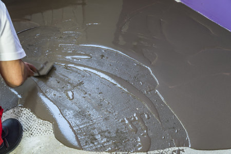 House under construction. Worker puts a self leveling screed on cement floorの写真素材