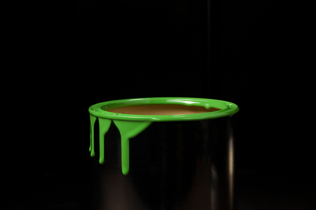 Colorful paint leaking down on wall of metal bucket. Isolated over black backgroundの写真素材