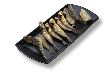 Delicious fried small fish with lemon in modern black plateの写真素材