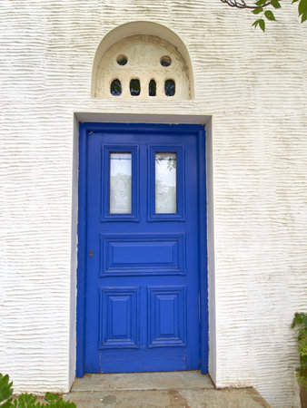 blue door with marble bass-relief on white wall, mediterranean island