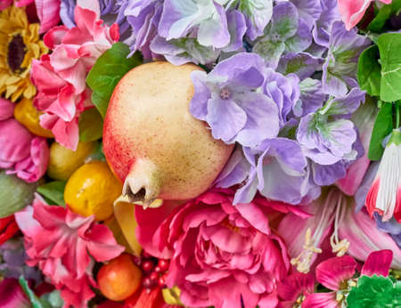 fake pomegranate and flowers closeup, colorful backgroundの写真素材